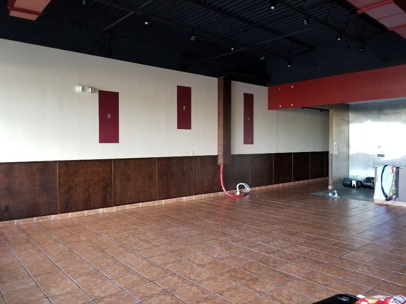 Empty commercial space with dark wainscot paneling, painted walls and a tile floor
