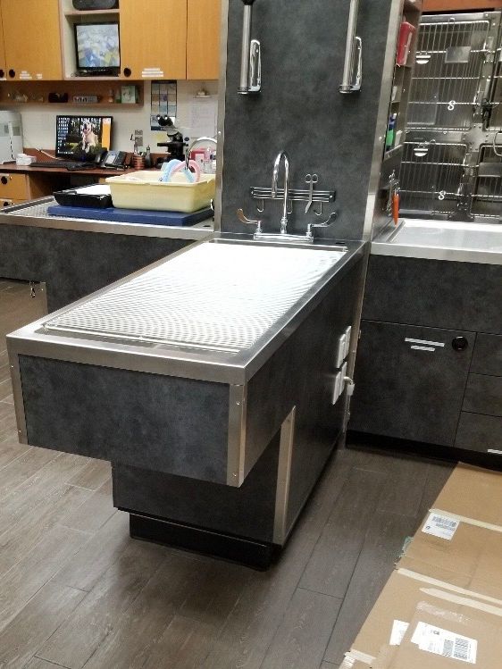 Finished stainless steel veterinary exam and wet table with a grated top and dark laminate base