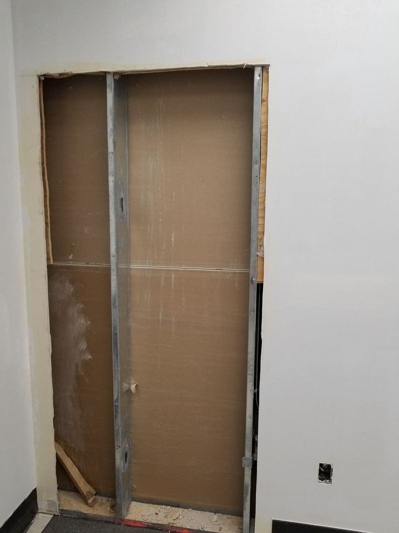 Commercial wall opening with exposed steel studs and backing, before a door was framed in